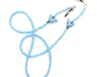 May include: A light blue beaded eyeglass chain. The chain features small, round beads and decorative blue bird charms with floral accents. The chain is designed to hold eyeglasses and has silver-toned attachments for the glasses.