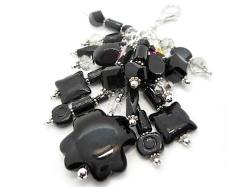 May include: A black and silver charm with a cluster of black and clear beads. The charm is attached to a silver chain.