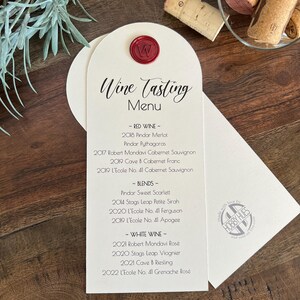 May include: An arched cream-colored wine tasting menu card featuring a red wax seal with the letter W. The text lists various red wines, blends, and white wines. A circular logo for Hobby Hues is printed on the lower right side of the card.