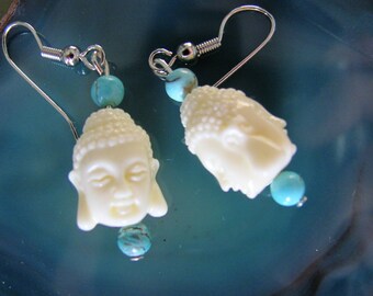May include: A pair of silver earrings with white Buddha head charms and turquoise beads.