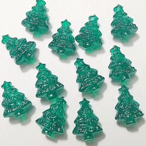 May include: Twelve green glitter Christmas tree shaped ornaments. The ornaments are made of glass and have a star on top.