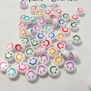 May include: White, multi-colored smiley face beads. The beads have a smiling face design in various colors, including pink, green, blue, yellow, and purple. The text "Multi-Colored" is above the beads.