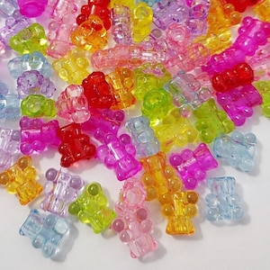 May include: A large pile of colorful gummy bear shaped beads. The beads are translucent and have a shiny finish.