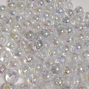 May include: A large pile of iridescent clear glass beads. The beads are round and have a rainbow sheen.