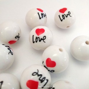 May include: White round beads with a red heart and the word "love" written in black.