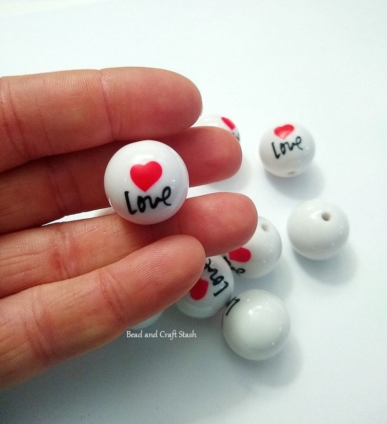 May include: White ceramic beads with a red heart and the word "love" written in black.
