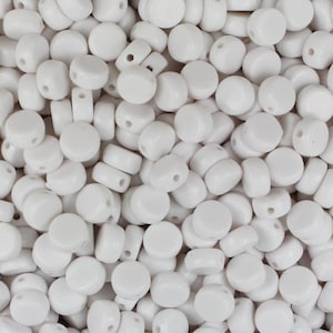 May include: A close-up view of a large quantity of white round beads with two holes in each bead. The beads are smooth and glossy.