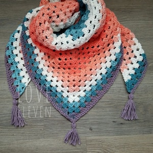 May include: A crocheted triangular shawl with a gradient of coral, white, teal, and purple. The shawl has a fringe on each end.