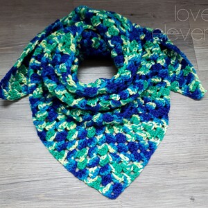 Op de afbeelding: Een driehoekige gehaakte sjaal in tinten blauw, groen en geel. De sjaal is gemaakt met een granny square steekpatroon.