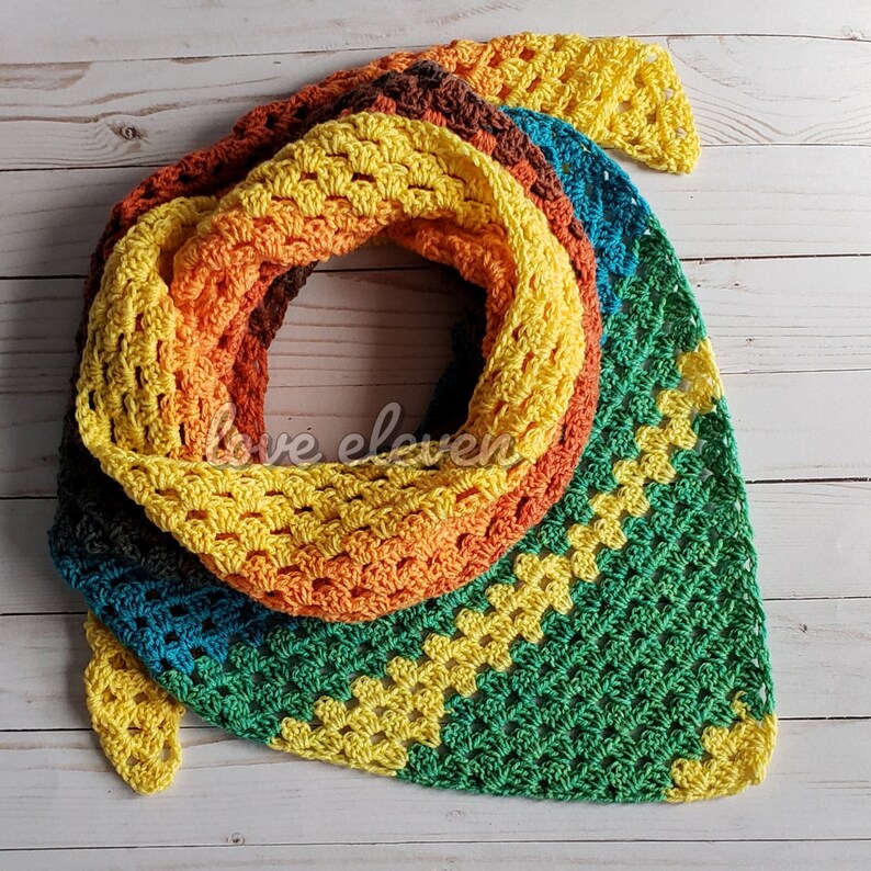 May include: A crocheted scarf in shades of green, yellow, orange, and brown. The scarf is made with a variety of stitches, including granny squares.