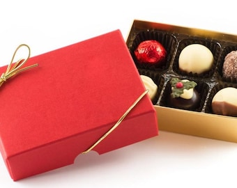 May include: A red box with a gold ribbon tied around it. The box is open and reveals a gold box filled with six assorted chocolates.