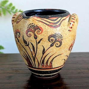 May include: A white ceramic mug with a black handle and the text "But First, Coffee" in a handwritten style. The mug is on a white surface. The mug is approximately 4 inches tall.