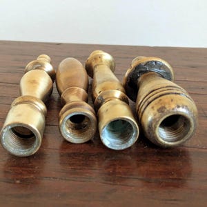 Pode incluir: Quatro cabos de selos de cera de lat&atilde;o antigos. Cada cabo tem uma forma &uacute;nica, com uma base roscada para fixar um selo. Os cabos variam em tamanho e design, mostrando sinais de idade e uso.