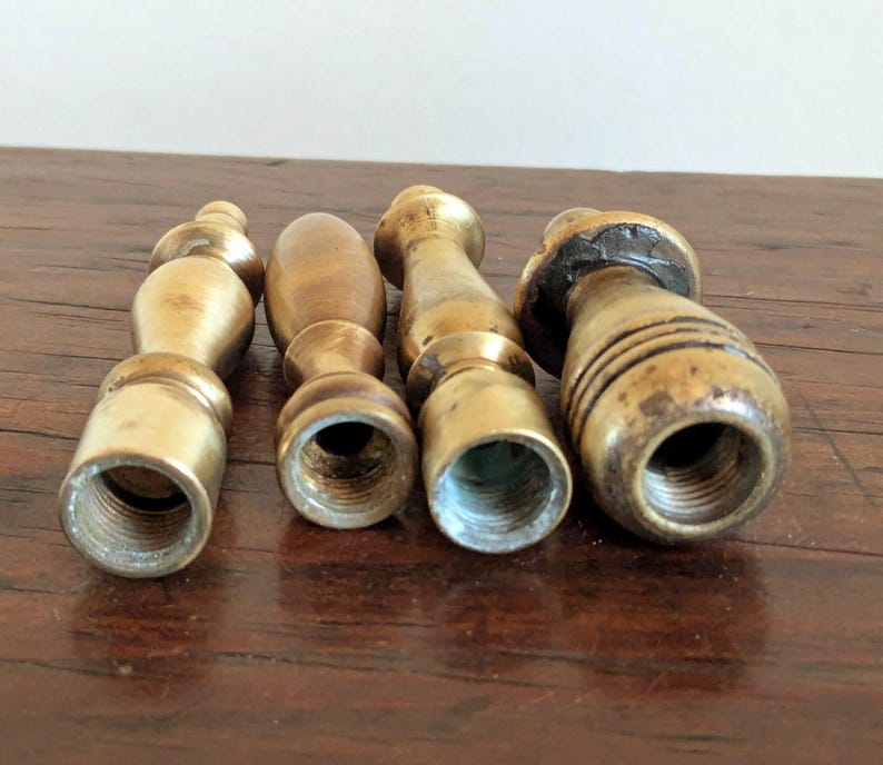 Pode incluir: Quatro cabos de selos de cera de lat&atilde;o antigos. Cada cabo tem uma forma &uacute;nica, com uma base roscada para fixar um selo. Os cabos variam em tamanho e design, mostrando sinais de idade e uso.