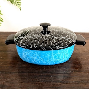 May include: A vintage blue and black enamel casserole dish with a lid. The blue base features a white squiggly pattern, while the lid is black with a similar white design. It has black handles and a black knob.
