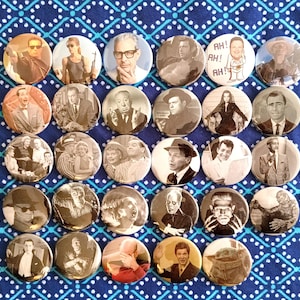 May include: A collection of round pinback buttons featuring black and white images of classic movie stars and characters. The buttons are arranged on a blue and white patterned fabric.