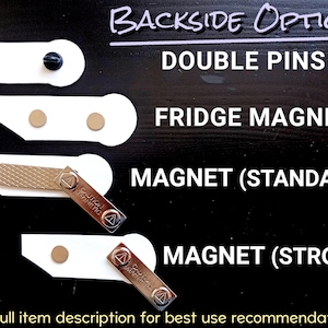 May include: A display showing four backside options for an item: double pins with black clutches, a fridge magnet with two circular magnets, a standard magnet bar with a metal plate, and a strong magnet bar with a single circular magnet.