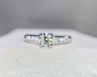 May include: A silver ring with a single round, clear gemstone surrounded by smaller, clear gemstones.