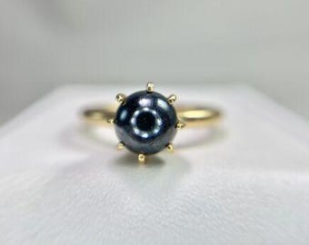 Puede incluir: Un anillo de oro con una perla negra engastada en garras.