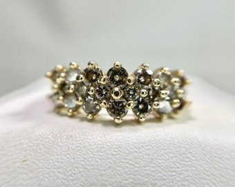 May include: A gold band ring with a cluster of small, round, brown diamonds set in a floral pattern.