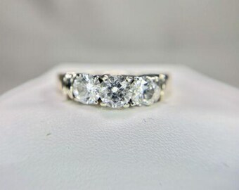 May include: A silver band ring with three round clear stones set in a row.