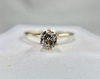 Op de afbeelding: Een gouden ring met een kussen geslepen diamant. De diamant heeft een lichtbruine kleur en is gezet in een vier-klauw zetting.