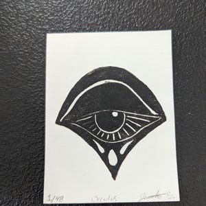 May include: Black and white print of an eye with a teardrop design. The print is numbered 1/48 and signed "Occulus".