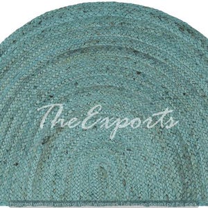 Puede incluir: Una alfombra semicircular en color verde azulado apagado. La alfombra está hecha de material tejido, con una superficie texturizada. El texto "The Exports" está impreso en blanco en el centro de la alfombra.