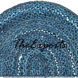 May include: A half-circle rug in shades of blue, with a braided texture. White accents create a striped pattern. The text "The Exports" is written across the center of the rug.