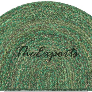 May include: A semi-circular rug in shades of green, with a braided texture. The rug has a natural, earthy appearance. The text "The Exports" is written across the centre of the rug.