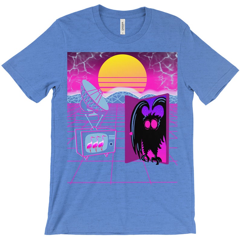 May include: A blue t-shirt with a retro-style graphic featuring a creature with large eyes emerging from a doorway, a satellite dish, a television with pink flamingos, and a sunset.