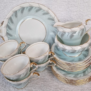 May include: A vintage tea set with a light blue and gold design. The set includes a teapot, creamer, sugar bowl, and four teacups and saucers.