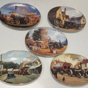 Puede incluir: Cinco platos ovalados decorativos con bordes dorados. Cada plato presenta una escena vintage diferente con vehículos y maquinaria a vapor. Los platos representan entornos rurales y urbanos con ilustraciones detalladas.
