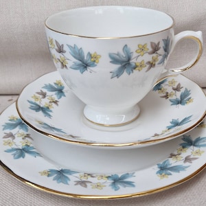 Queen Anne Bone China Trio decorated with small yellow flowers and blue leaves.
