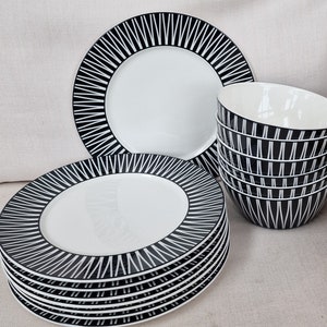 May include: A set of black and white patterned dinner plates and bowls. The plates have a white centre and a black and white geometric pattern around the edge. The bowls have a black and white geometric pattern.