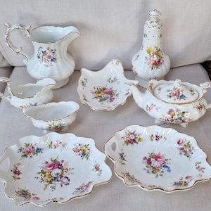 Puede incluir: Un juego de seis tazas de té y platillos de porcelana vintage con motivos florales. El juego incluye una tetera, una jarra de crema, un azucarero y dos platos pequeños.
