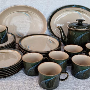 May include: A set of green and brown stoneware dinnerware with a swirling pattern. The set includes plates, cups, saucers, and a teapot.
