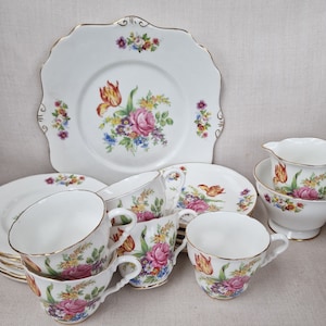 Può includere: Un set da tè vintage floreale con un delicato motivo floreale in tonalità rosa, giallo e blu. Il set comprende un piatto da torta, una brocca per la panna, tazze da tè e piattini.