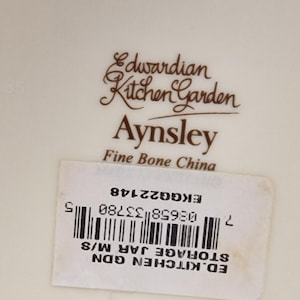 May include: A white ceramic storage jar with a brown Edwardian Kitchen Garden Aynsley Fine Bone China label. The label also includes a barcode and the text "ED. KITCHEN GDN STORAGE JAR M/S 7 08658 33780 5 EKG GG22148".
