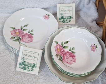 May include: White porcelain plates and bowls with a scalloped edge and a floral rose design. The roses are pink with green leaves. The image also includes two cards with the text "The National Trust, Helstone Roses, Fine English Bone China."