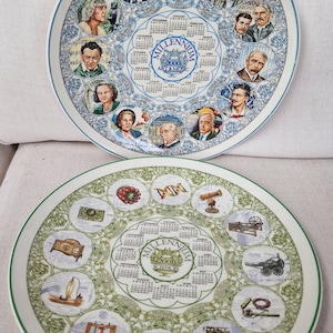 May include: Two decorative ceramic plates with a green and white border. The plates feature a calendar for the year 2000 and 2001. The 2000 plate has a blue and white background with a calendar for the year 2000 and the text "Millennium 2000 Art & Music". The 2001 plate has a green and white background with a calendar for the year 2001 and the text "Millennium 2001 Sciences".