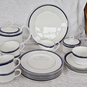 Puede incluir: Un juego de tazas de té, platillos y una tetera de porcelana azul y blanca. El juego incluye una jarra de crema y un azucarero. La porcelana tiene un delicado borde azul.