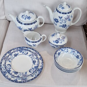 May include: A set of blue and white floral patterned teacups, teapot, creamer, sugar bowl, and two plates. The set is made of porcelain and has a delicate floral design.