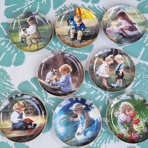 Op de afbeelding: Set van acht decoratieve borden met kinderen in verschillende scènes. Elk bord heeft een gouden rand en een witte achtergrond met een kleurrijke illustratie. De borden tonen kinderen die spelen, lezen en met dieren omgaan.