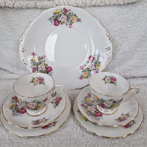 以下が含まれることがあります： 白い磁器のティーセット、バラの花柄。 セットには、大きなサービングプレート、2つのティーカップ、2つのソーサーが含まれます。 各ピースには金のトリムが付いています。