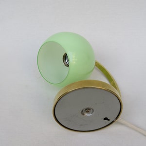 Peut inclure: Une lampe de bureau en laiton avec un abat-jour en verre vert. La lampe a une base ronde et un bras incurv&eacute;.