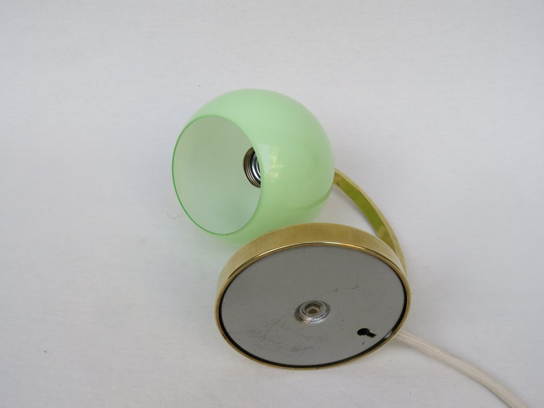 Peut inclure: Une lampe de bureau en laiton avec un abat-jour en verre vert. La lampe a une base ronde et un bras incurv&eacute;.