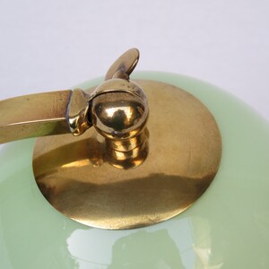 Peut inclure: Une lampe vintage en laiton et verre vert avec un abat-jour rond et un bouton d&eacute;coratif sur le dessus.