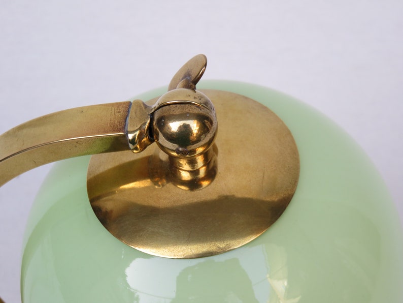Peut inclure: Une lampe vintage en laiton et verre vert avec un abat-jour rond et un bouton d&eacute;coratif sur le dessus.