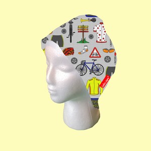 May include: Gray cycling cap with a colorful design featuring bicycles, helmets, and other cycling-related imagery. The text "Cycling is my therapy" is printed on the cap.